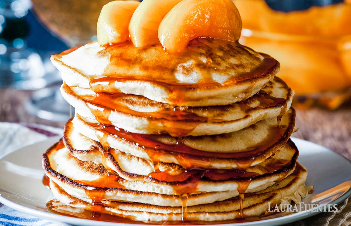 large stack of pancakes topped with peach slices