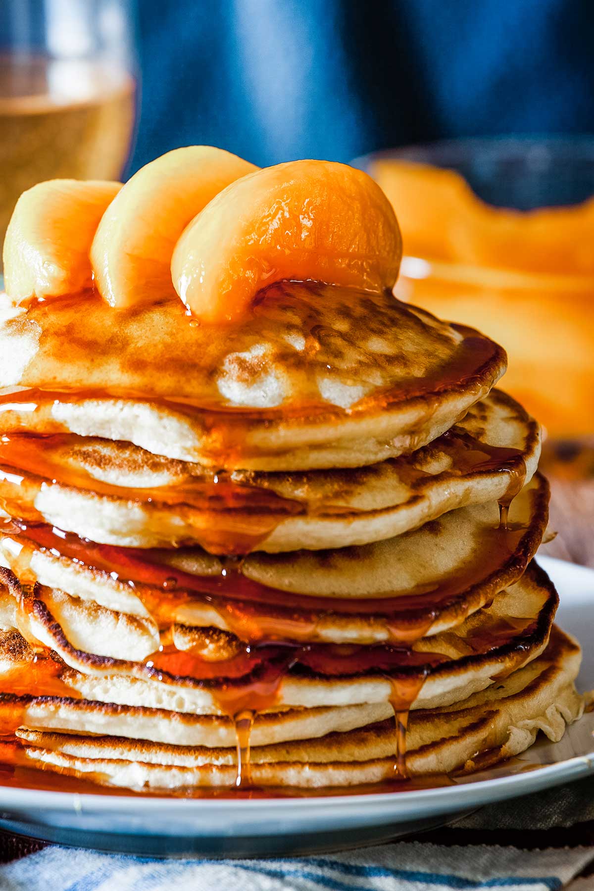 large stack of pancakes topped with peach slices