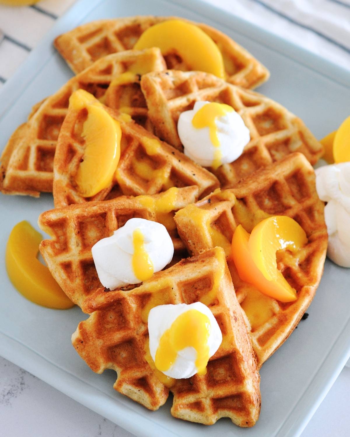 waffles topped with with whipped cream, peach slices and peach syrup