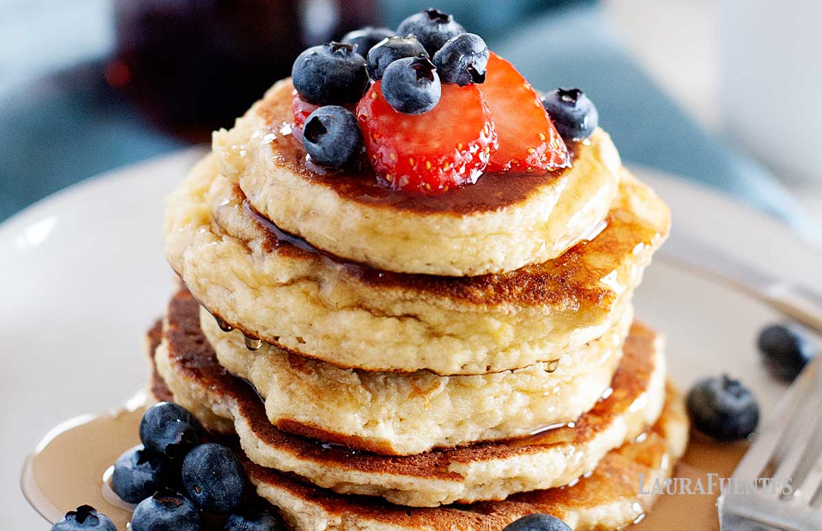 stack of almond flour pancakes topped with strawberries and blueberries