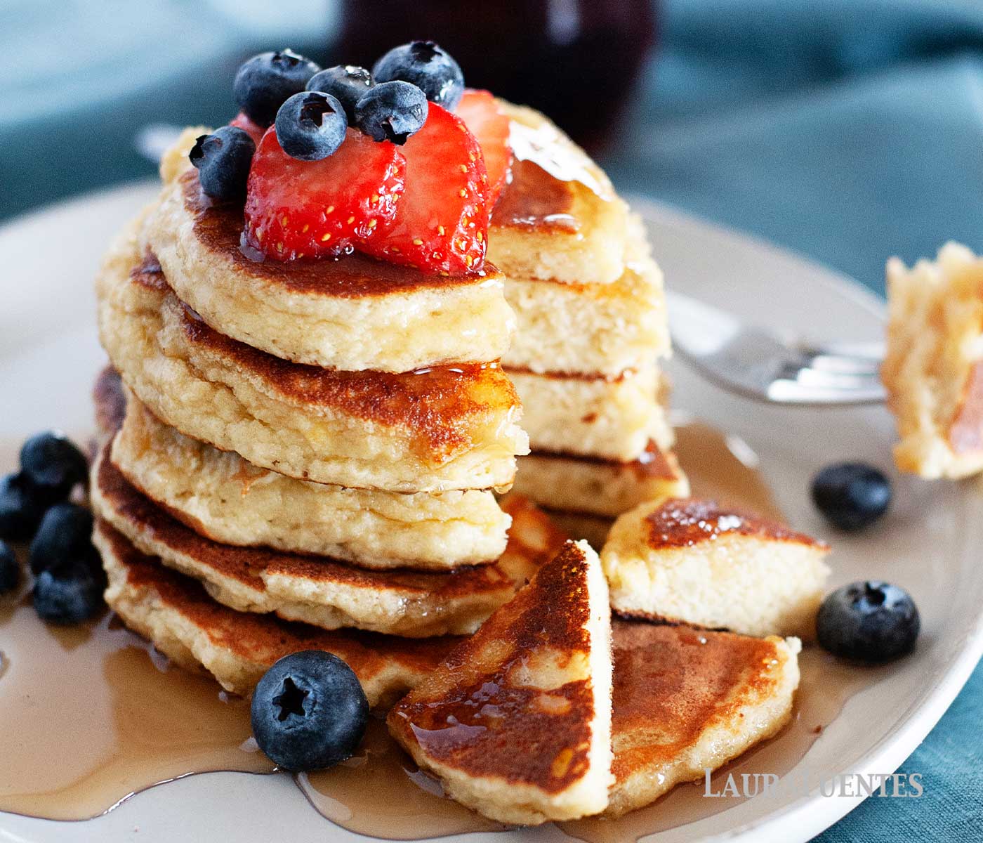 almond flour pancakes stacked on a plate with strawberries and syrup