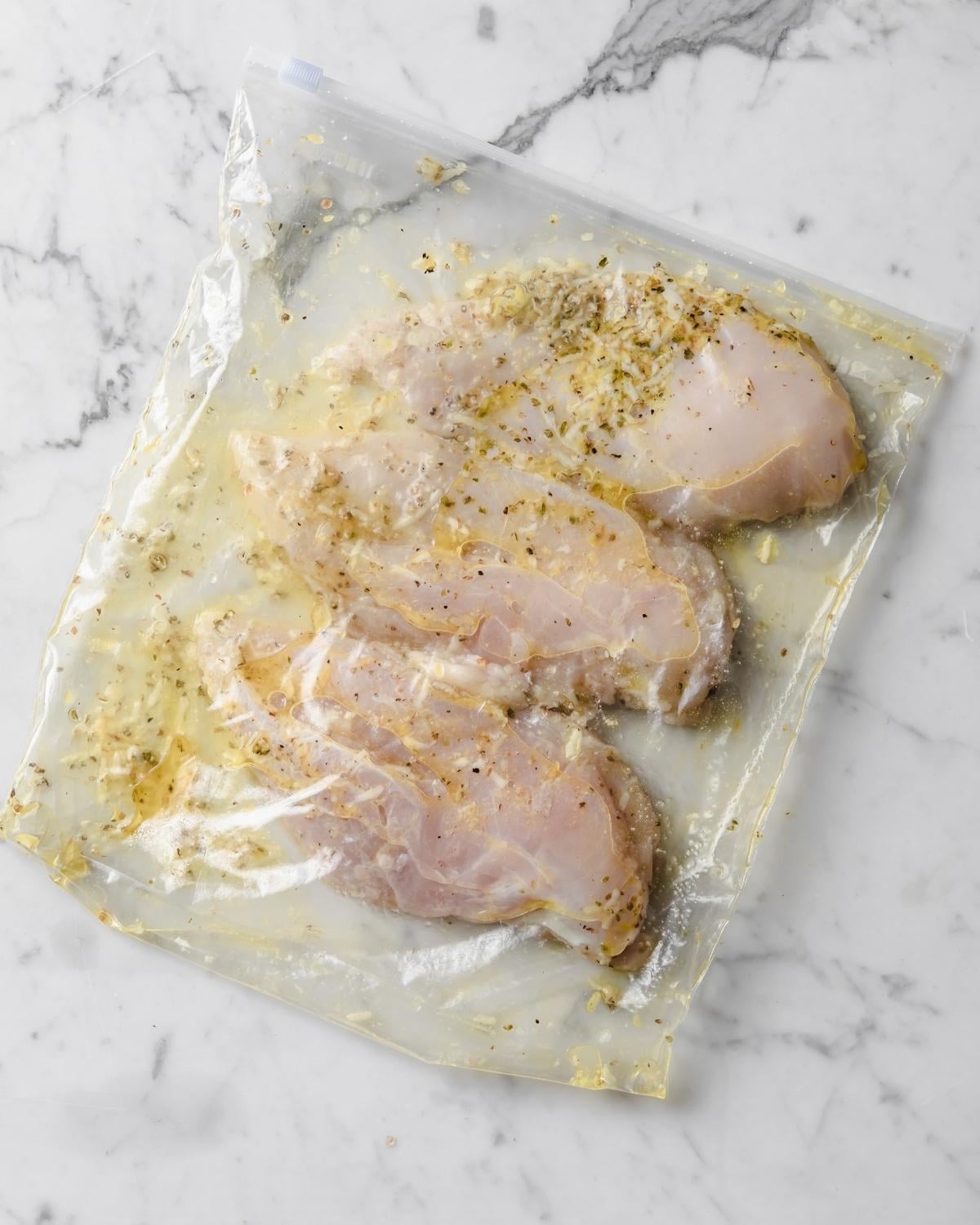 zip bag with marinade and three chicken breasts