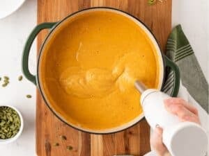 blending acorn squash soup with an immersion blender