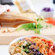 bottle filled with homemade thai peanut dressing being poured over a salad
