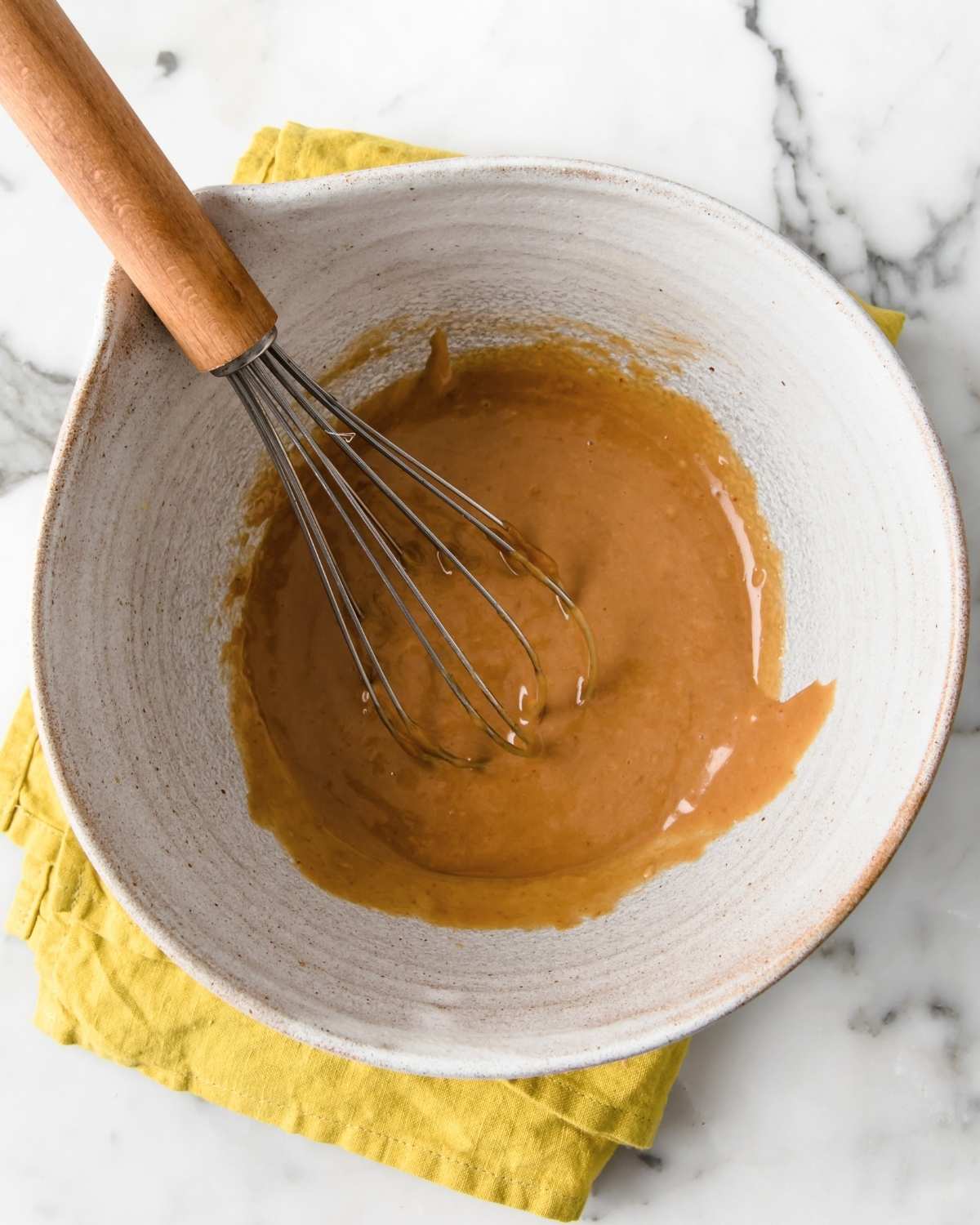 homemade thai peanut dressing mixed in a bowl with a wire whisk