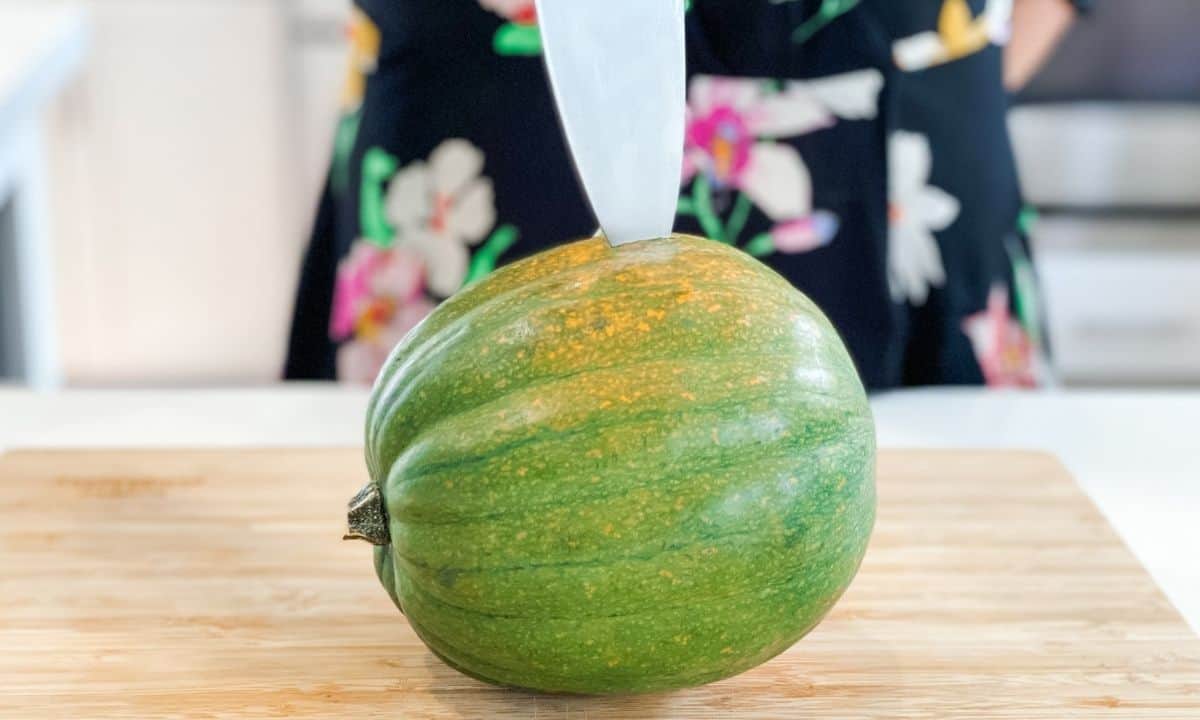 woman poking a whole acorn squash with a knife