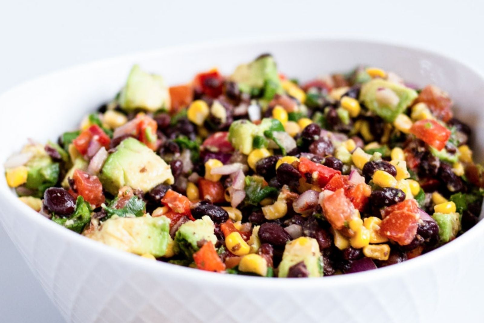 a bowl of southwest quinoa salad with avocado, corn and beans