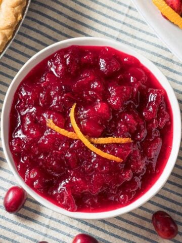 overhead view of a bowl of orange cranberry sauce at a table