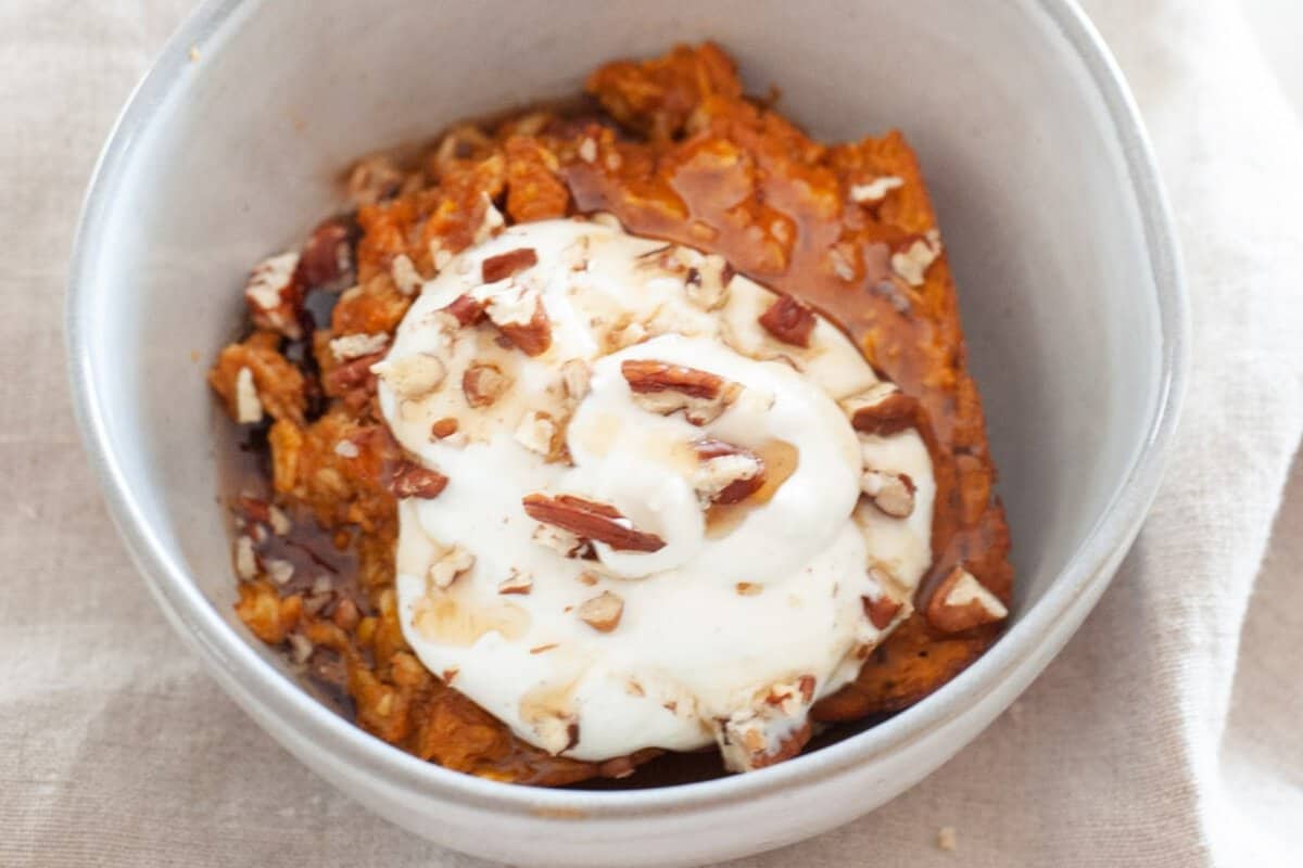 a bowl of pumpkin baked oatmeal topped with sour cream and nuts