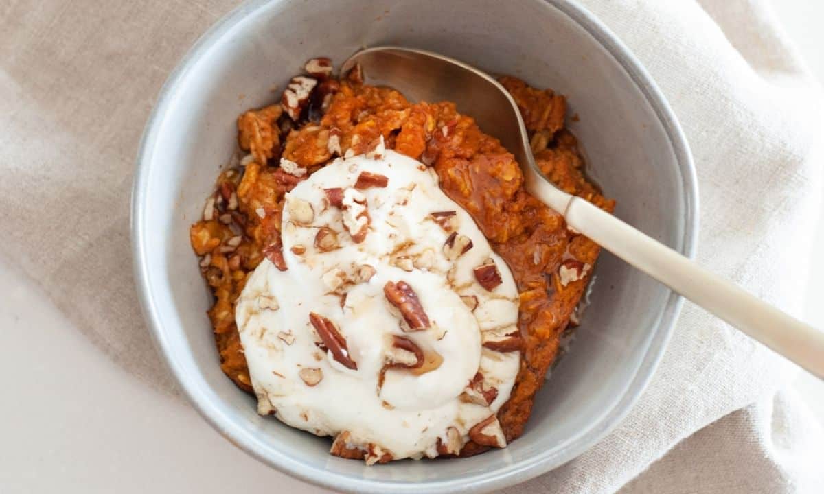 a bowl of pumpkin baked oatmeal topped with sour cream and nuts