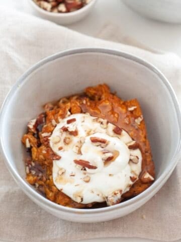 a bowl of pumpkin baked oatmeal topped with sour cream and nuts