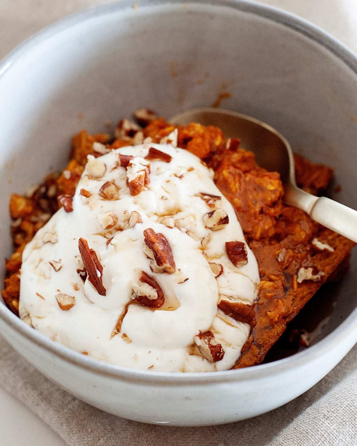 closeup of pumpkin baked oatmeal topped with nuts and whipped cream