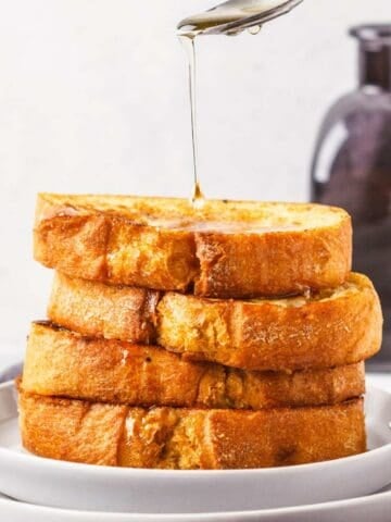 syrup being poured over a stack of four thick pumpkin French toast slices