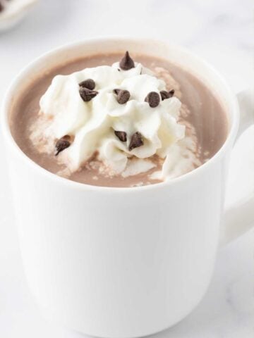 mug of homemade hot chocolate topped with whipped cream and chocolate chips