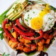 top view of a breakfast salad with avocado, sweet potatoes, bell pepper and a fried egg