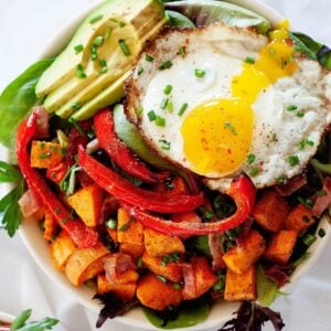 top view of a breakfast salad with avocado, sweet potatoes, bell pepper and a fried egg