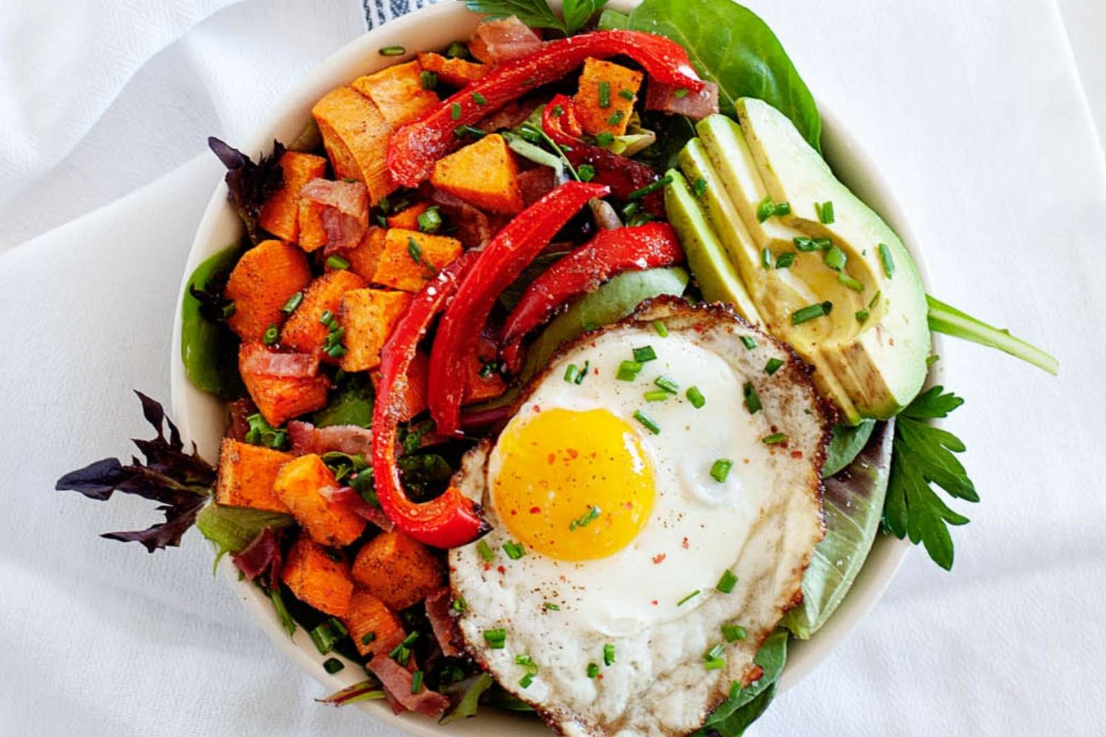 top view of a breakfast salad with avocado, sweet potatoes, bell pepper and a fried egg
