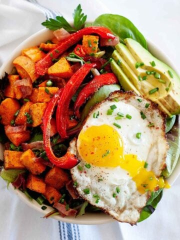 top view of a breakfast salad with avocado, sweet potatoes, bell pepper and a fried egg