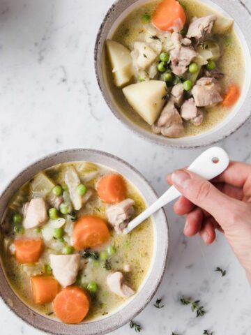 top view of two bowls of chicken stew, and a hand stirring one of them with a spoon