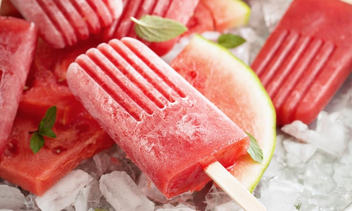 a watermelon popsicle over ice and watermelon pieces, surrounded by more popsicles