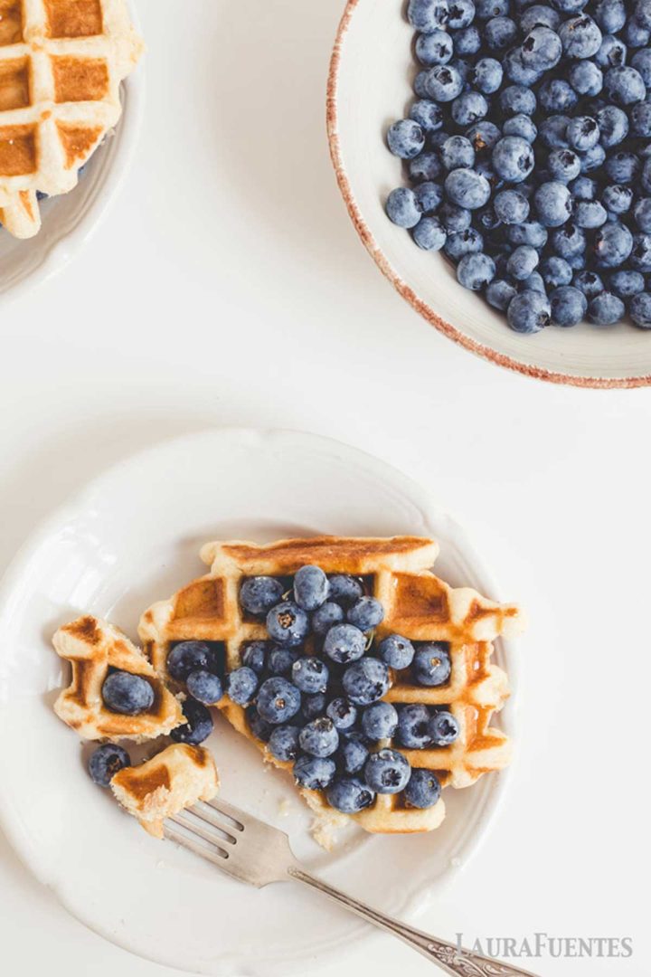 overhead view of waffles with blueberries, large bowl of blueberries to one side