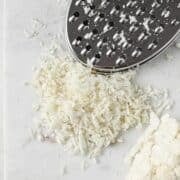 cauliflower rice, a cheese grater and a cauliflower chunk