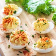 five deviled eggs on a wooden board