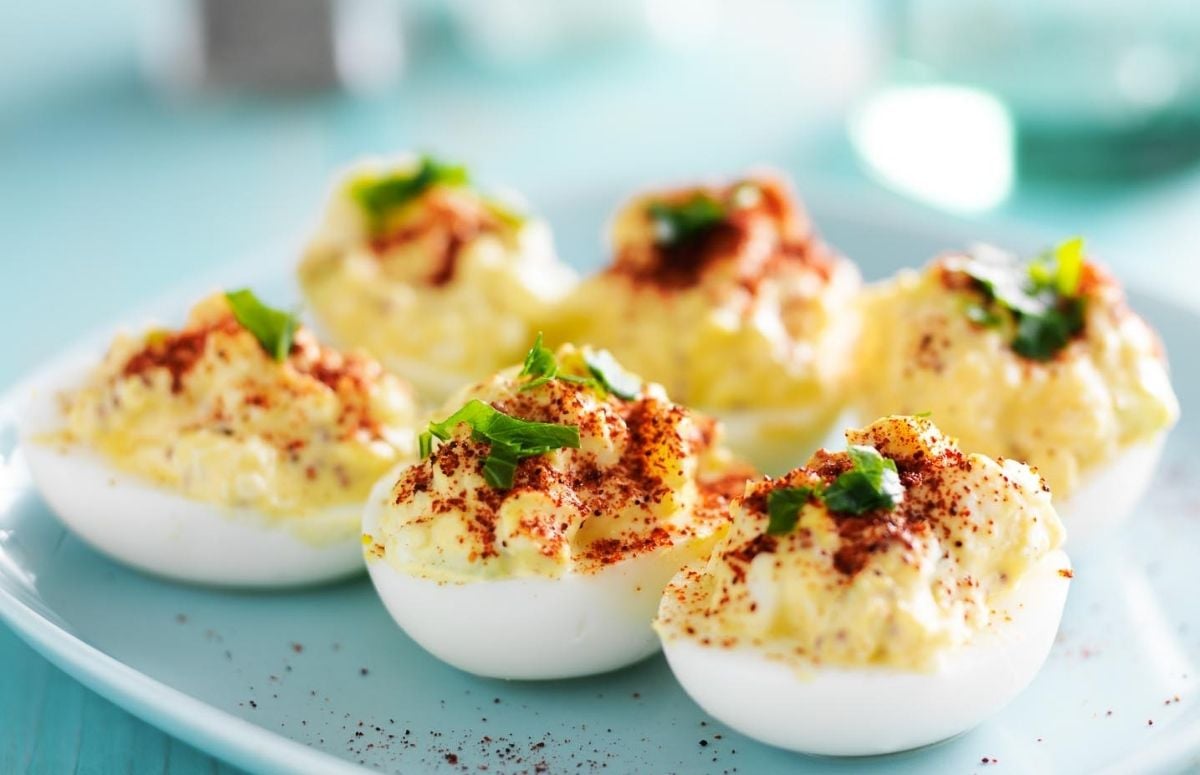 front view of classic angel eggs (also known as deviled eggs) on a blue plate topped with sprinkled paprika and chives