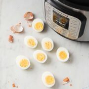 seven boiled egg halves on a countertop with an instant pot