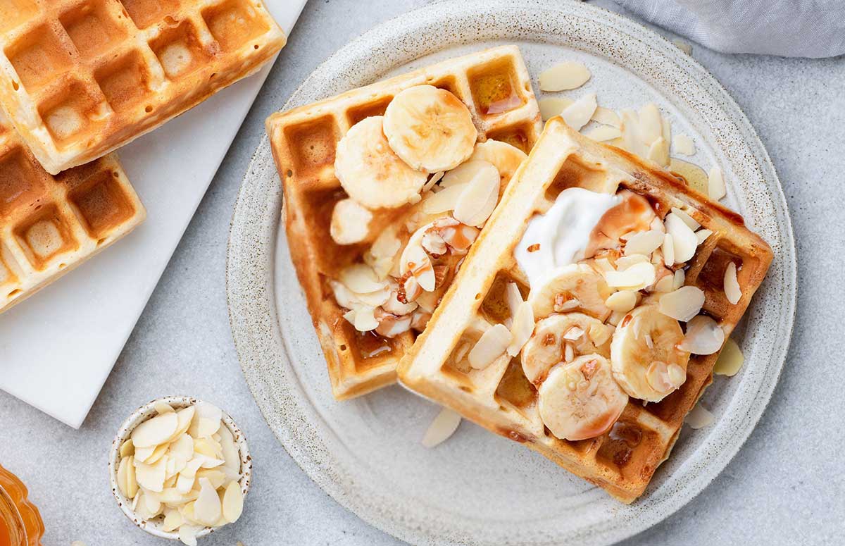 overhead view of two banana waffles topped with bananas on a plate