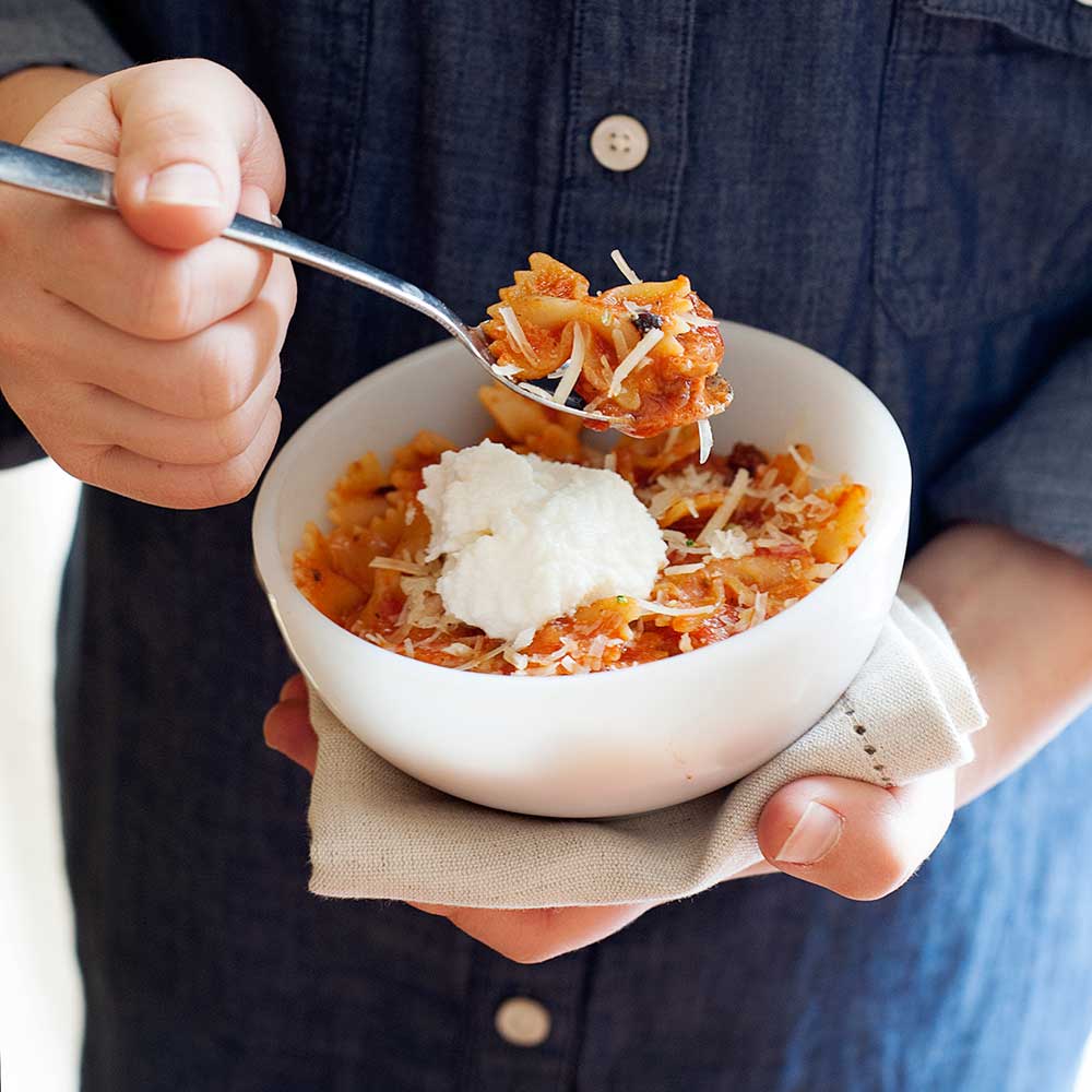 A kid holds a stovetop lasagna bowl
