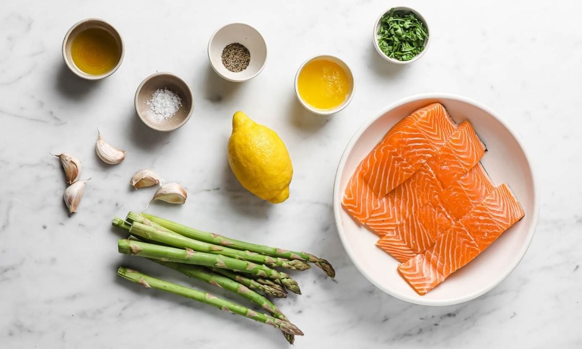 Ingredients for the recipe: raw salmon fillets, asparagus, olive oil, one lemon, garlic cloves, seasonings and chopped parsley