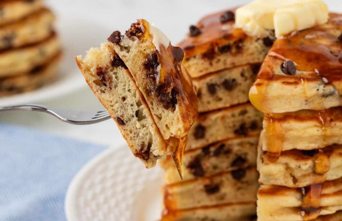 sliced stack of chocolate chip pancakes on a fork to show the fluffy texture and the chocolate chips inside
