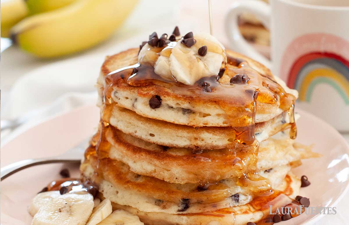 stack of chocolate chip pancakes with bananas and syrup