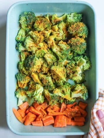 overhead view of roasted broccoli and carrots in a blue baking dish