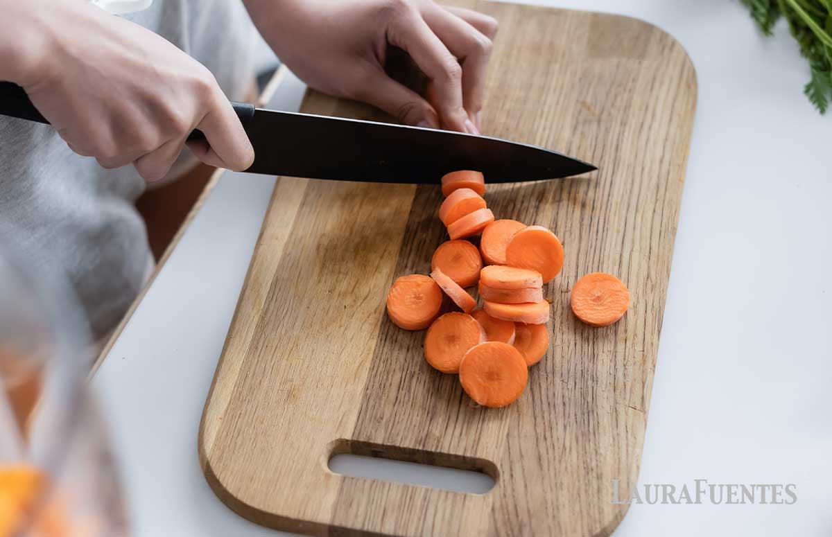 someone chopping carrots on a cutting board