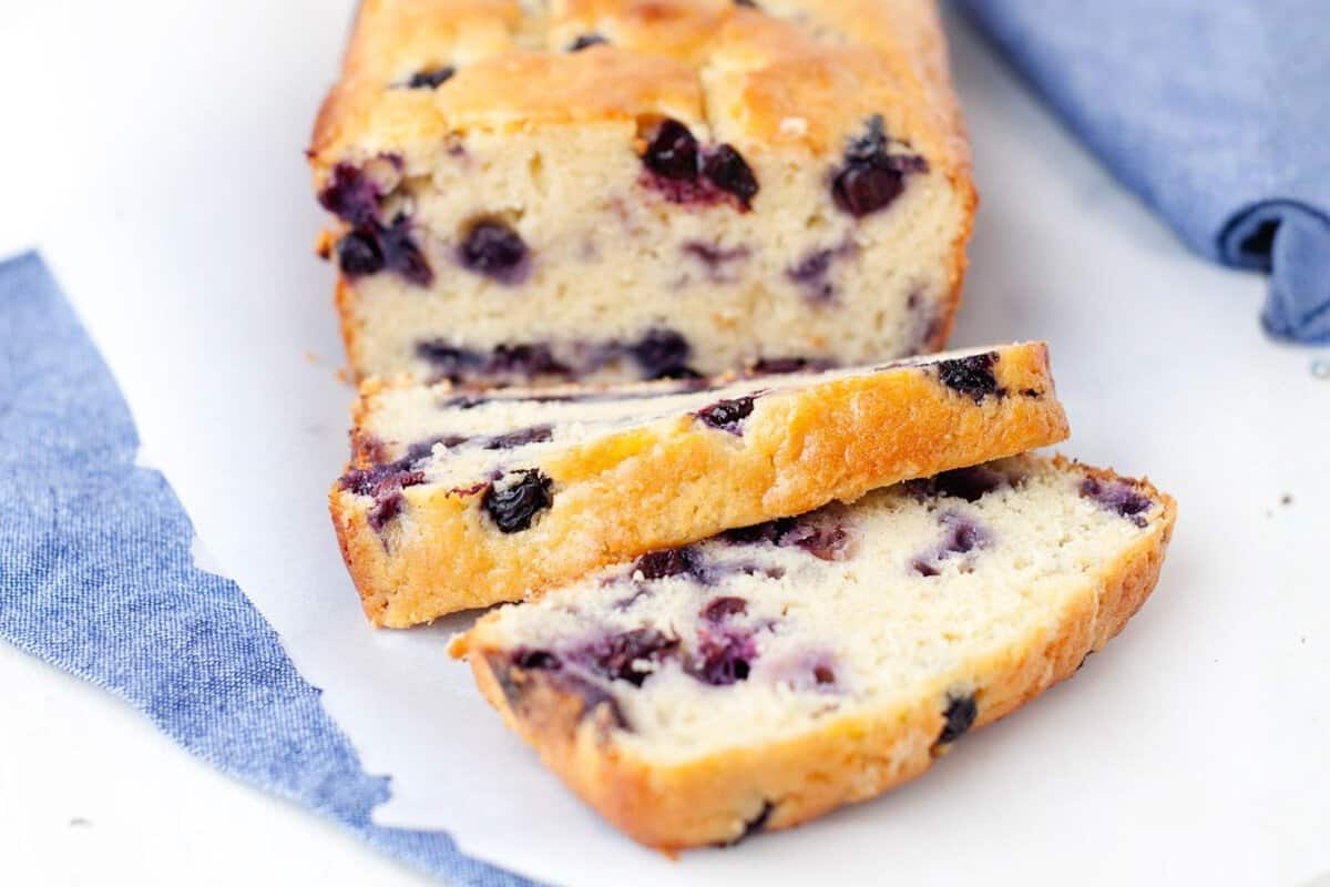 loaf of blueberry bread with two slices cut in the front