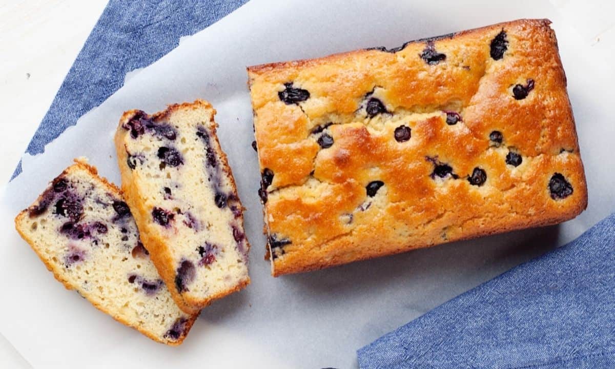 overhead view of a loaf of blueberry bread with two slices cut in the front