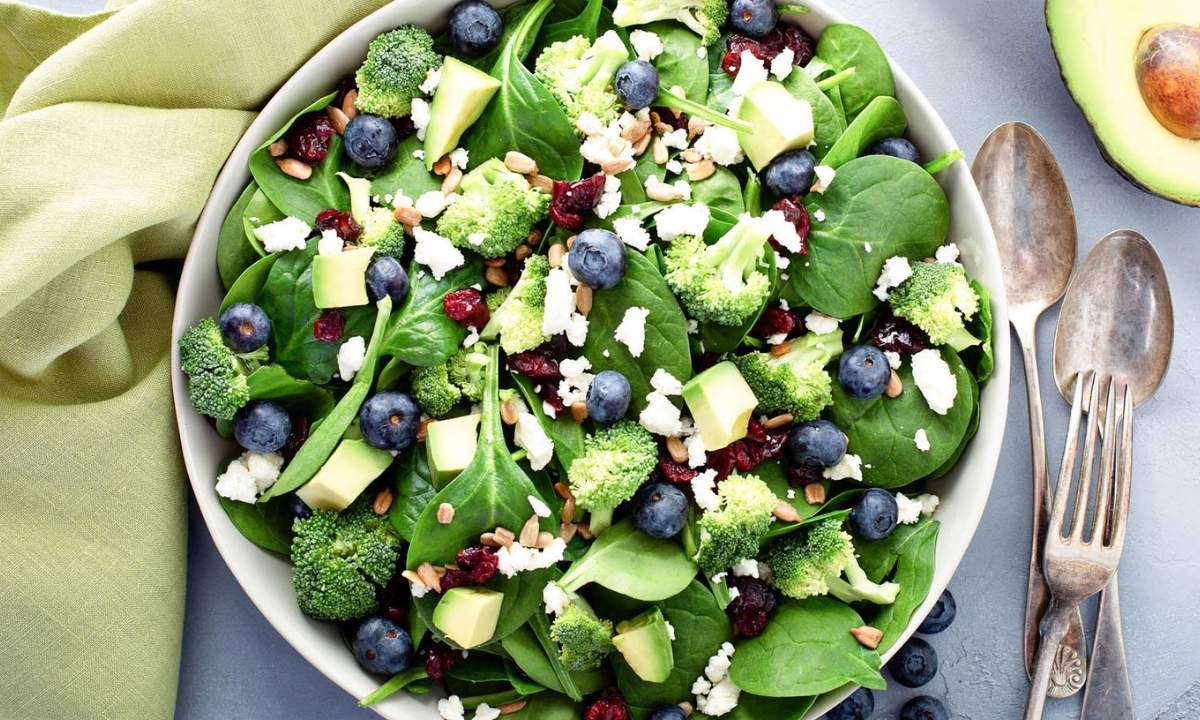 top view of blueberry spinach salad with broccoli and avocado in a large bowl