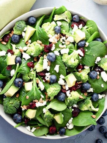 top view of blueberry spinach salad with broccoli and avocado in a large bowl