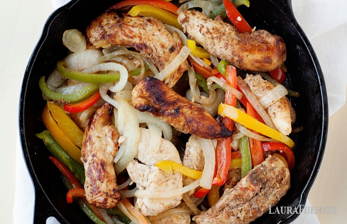 overhead view of skillet filled with chicken strips and roasted peppers and onions