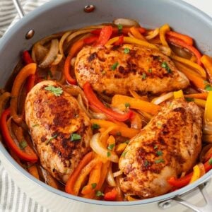 overhead view of a skillet with chicken with peppers and onions recipe