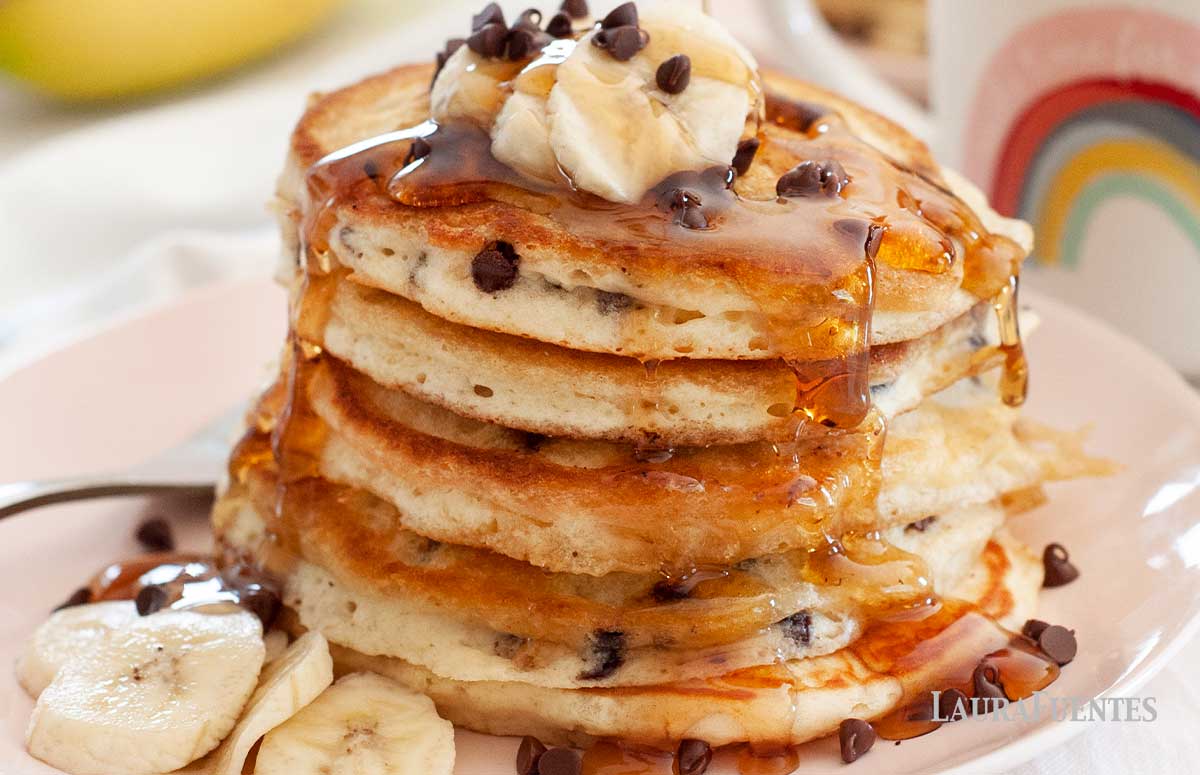 large stack of pancakes topped with bananas and chocolate chips