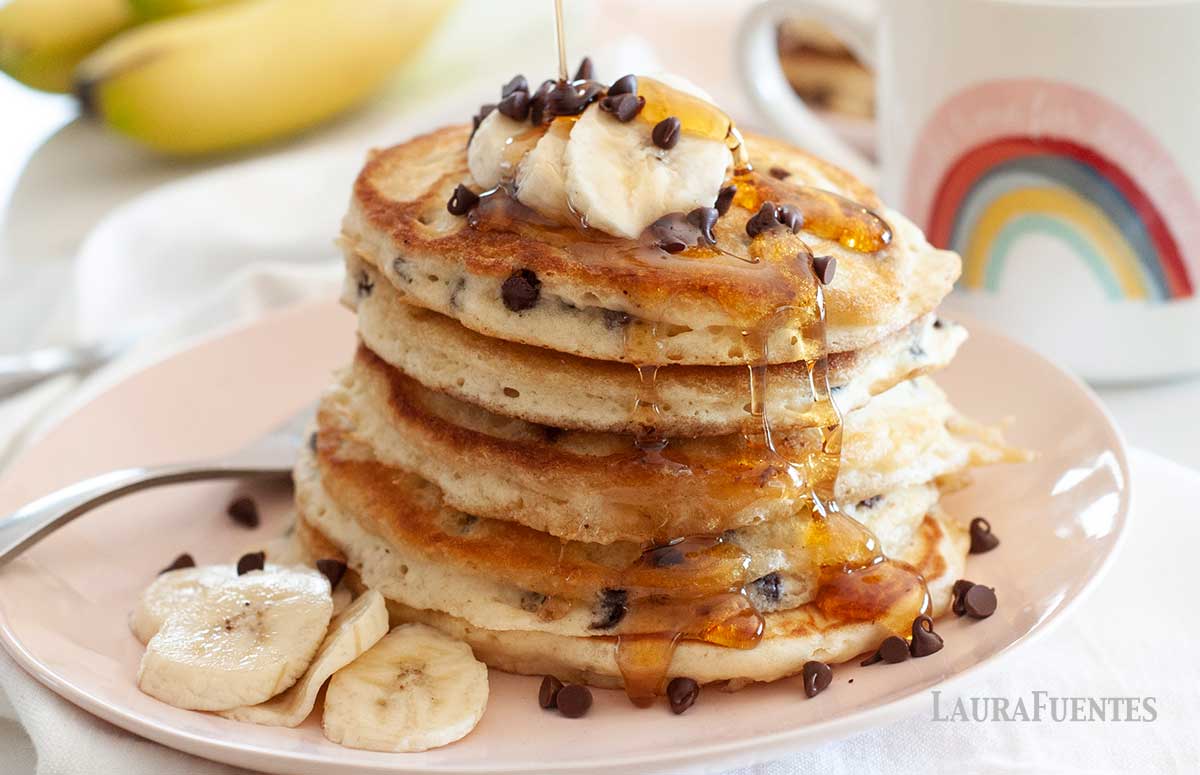 large stack of pancakes topped with bananas and chocolate chips