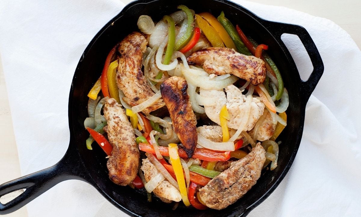 skillet with chicken strips and roasted peppers and onions