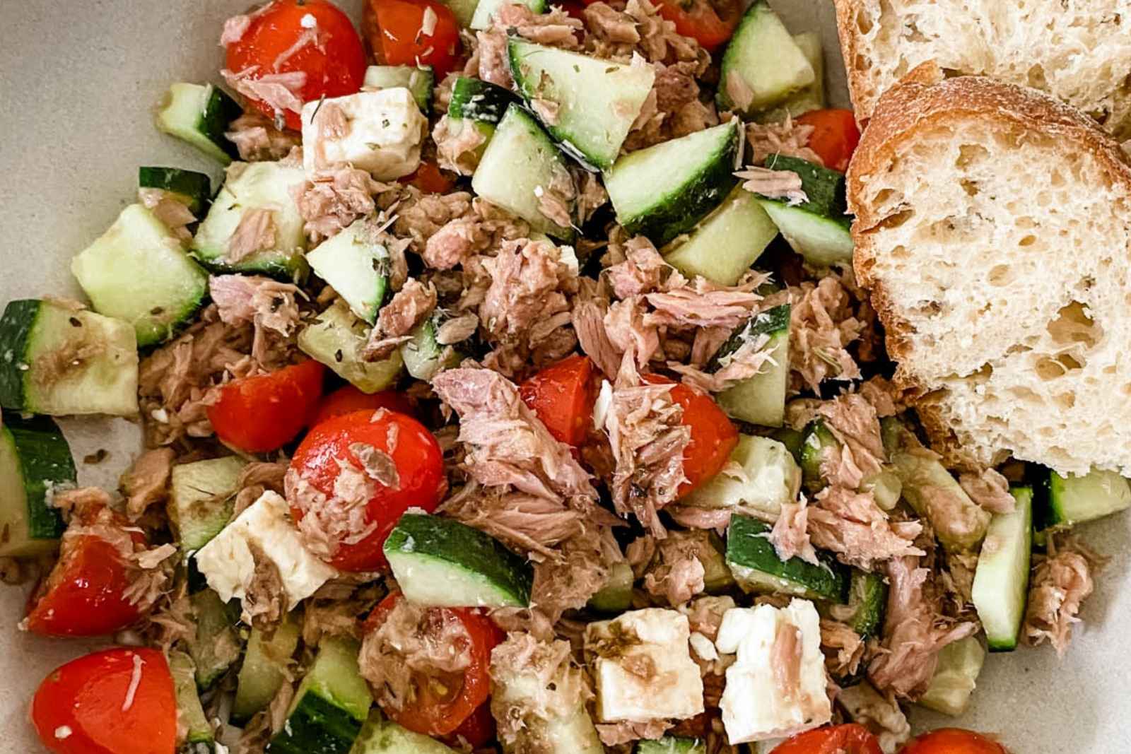 tuna salad with tomato and cucumber, and slices of bread on the side