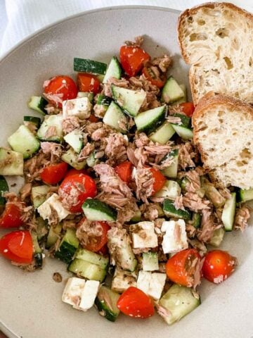 tuna salad with tomato and cucumber, and slices of bread on the side