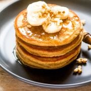 large stack of pumpkin banana pancakes topped with banana slices and nuts