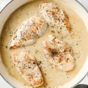 creamy garlic sauce in a pan with four chicken breasts