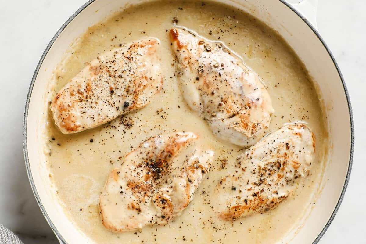 overhead of a creamy garlic sauce for chicken in a pan with cooked chicken inside